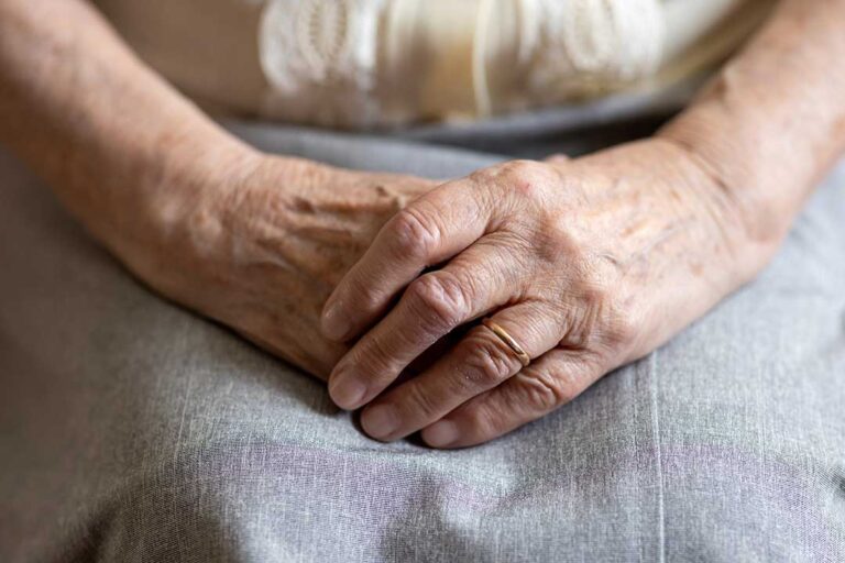 Older adult and caregiver sharing a calm conversation in a bright assisted living common room.